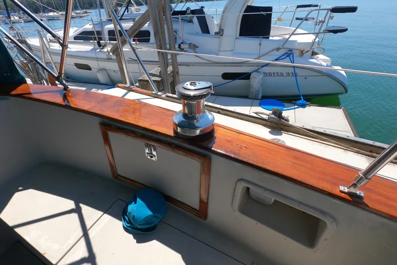Slide: The Image of 1978 CSY 44 sailboat deck with polished wood and winch, docked beside another boat. - 35
