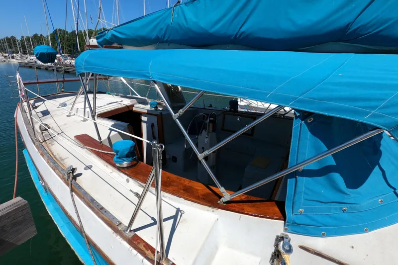 Slide: The Image of 1978 CSY 44 sailboat with blue canopy docked at marina, showcasing deck and cockpit area. - 4