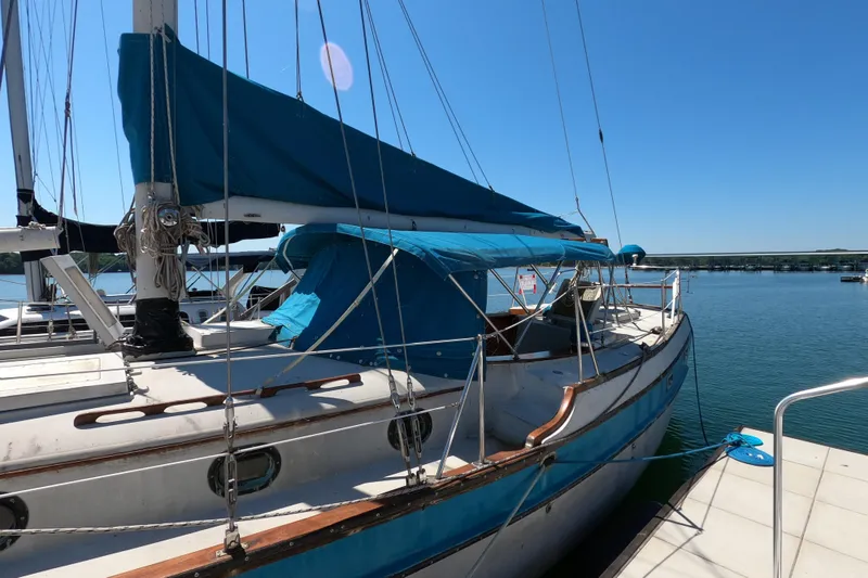 Slide: The Image of 1978 CSY 44 sailboat docked, featuring blue canvas covers and wooden accents on a sunny day. - 9