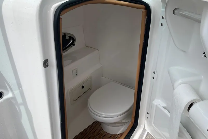 Slide: The Image of 2024 NauticStar 243 DC boat interior with compact marine toilet and storage. - 12