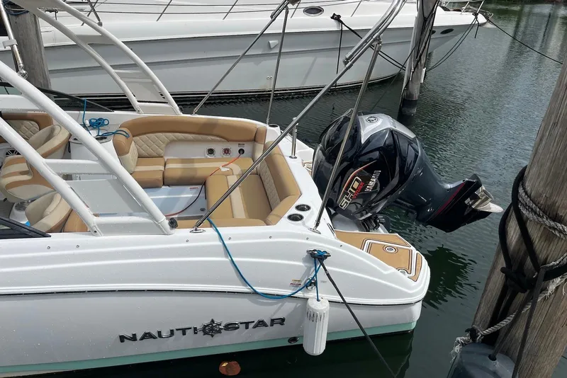 Slide: The Image of 2024 NauticStar 243 DC boat docked, featuring tan seating and Yamaha outboard motor. - 2