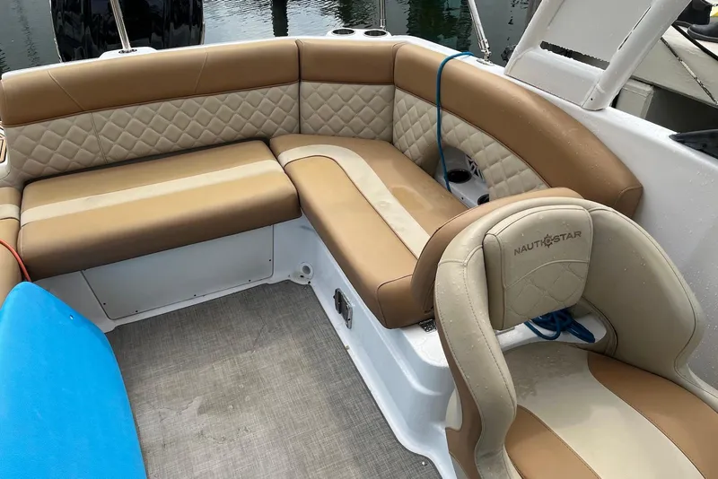 Slide: The Image of 2024 NauticStar 243 DC boat interior with tan and cream seating, featuring quilted upholstery. - 8