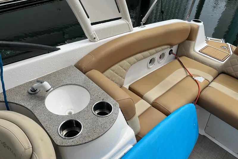 Slide: The Image of 2024 NauticStar 243 DC boat interior with sink, cup holders, and tan seating. - 9