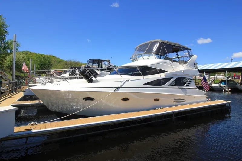 The Image of 2006 Silverton 38 Sport Bridge yacht docked at marina under clear blue sky. - 1