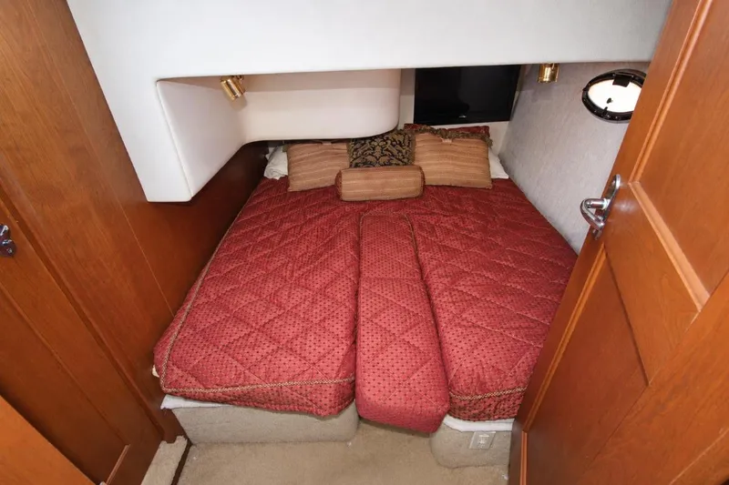 Slide: The Image of Cozy bedroom interior of 2006 Silverton 38 Sport Bridge with red bedding and wooden accents. - 13