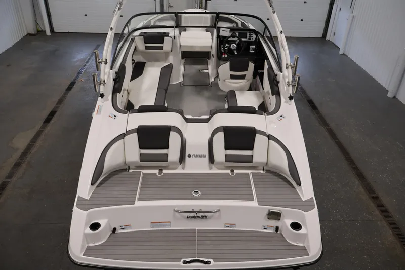Slide: The Image of 2021 Yamaha Boats AR210 interior view, showcasing seating and helm in a garage setting. - 10