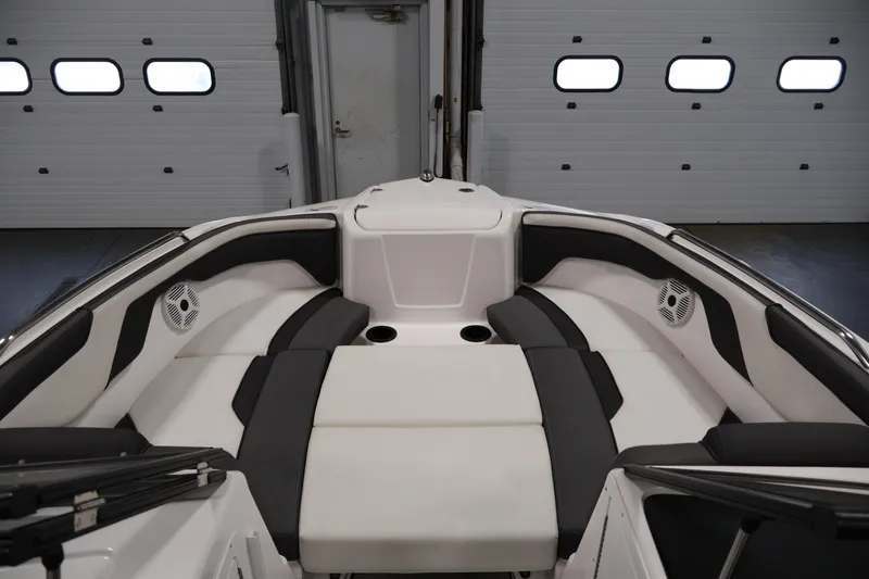 Slide: The Image of 2021 Yamaha AR210 boat interior with cushioned seating and cup holders in a garage. - 11