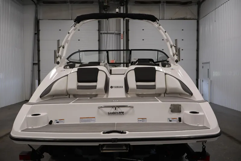 Slide: The Image of 2021 Yamaha Boats AR210 in a showroom, rear view showcasing seating and design. - 6