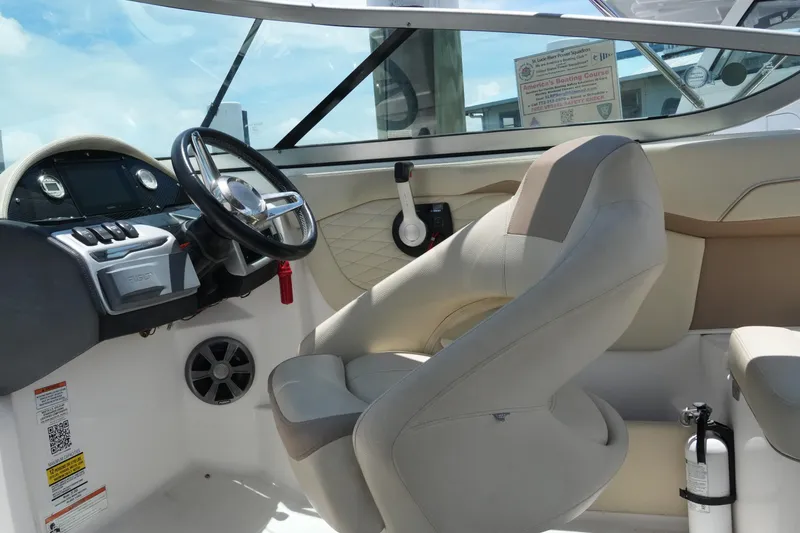 Slide: The Image of 2019 Regal 23 OBX boat interior with steering wheel, dashboard, and beige seating. - 23