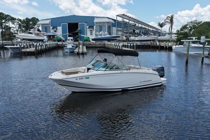 Slide: The Image of 2019 Regal 23 OBX boat docked at marina with blue building in background. - 5