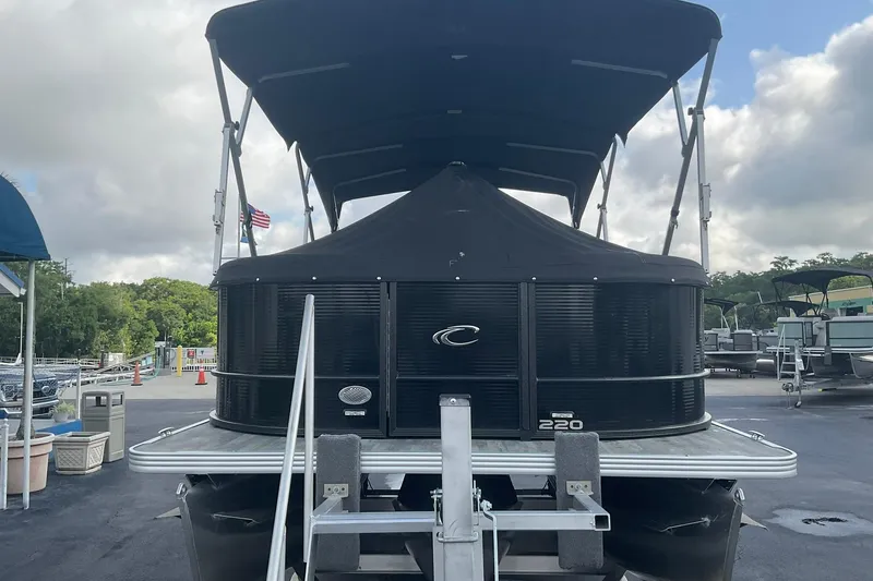 Slide: The Image of 2023 Crest Classic DLX 220 SLC pontoon boat with canopy, docked under cloudy sky. - 10