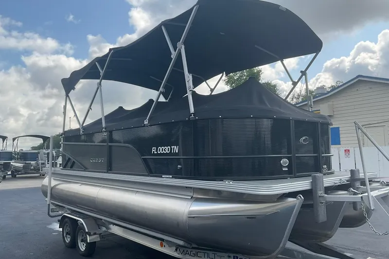 Slide: The Image of 2023 Crest Classic DLX 220 SLC pontoon boat on trailer, featuring black canopy. - 11