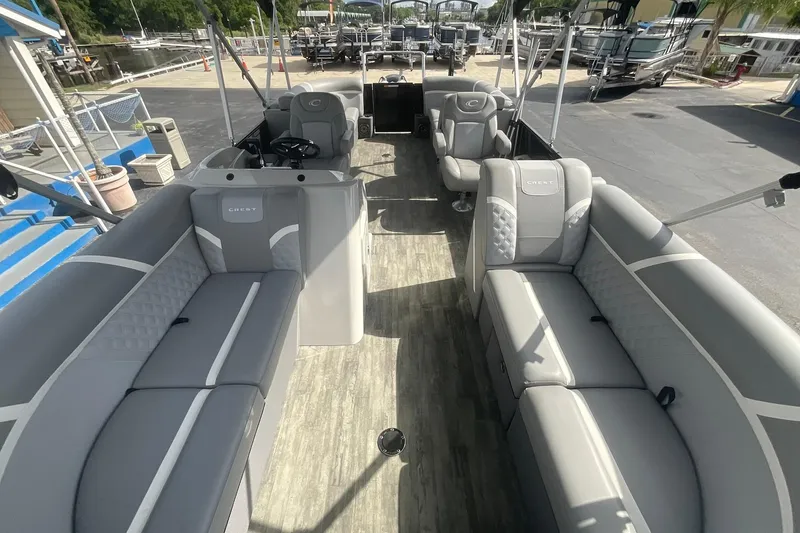 Slide: The Image of 2023 Crest Classic DLX 220 SLC pontoon boat interior with luxurious gray seating and spacious layout. - 16