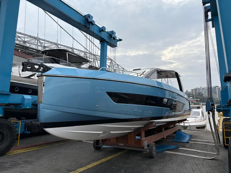 Slide: The Image of Schaefer V44 Yacht 2026 in shipyard, blue hull, crane in background. - 2