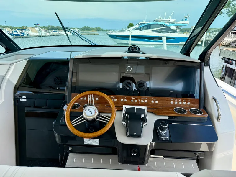 Slide: The Image of The cockpit of a 2027 Tiara Yachts 43LS with a sleek wooden steering wheel and modern instruments. - 15
