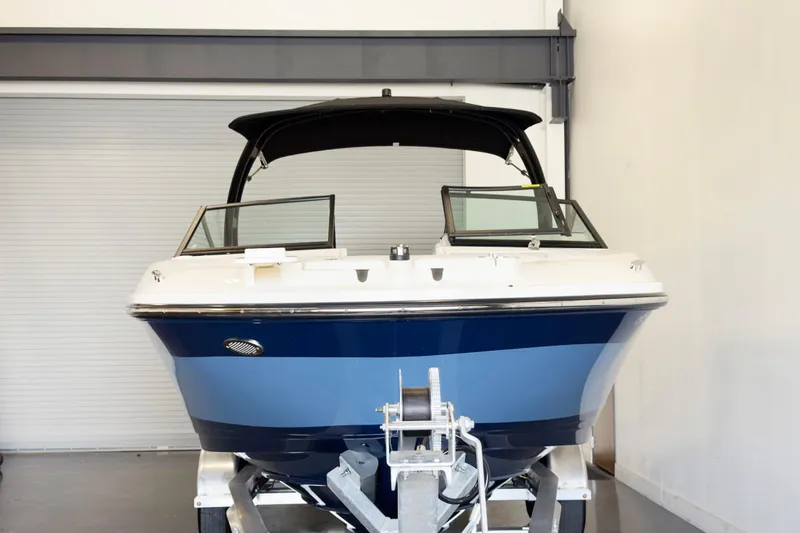 Slide: The Image of 2021 Sea Ray SPX 230 boat in showroom, front view with blue hull and black canopy. - 2