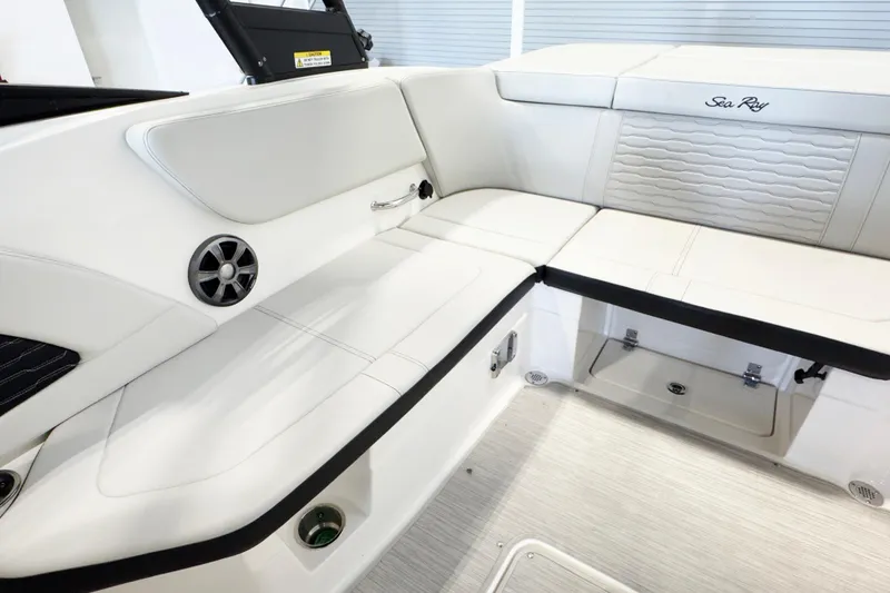 Slide: The Image of 2021 Sea Ray SPX 230 boat interior with white cushioned seating and storage compartments. - 9