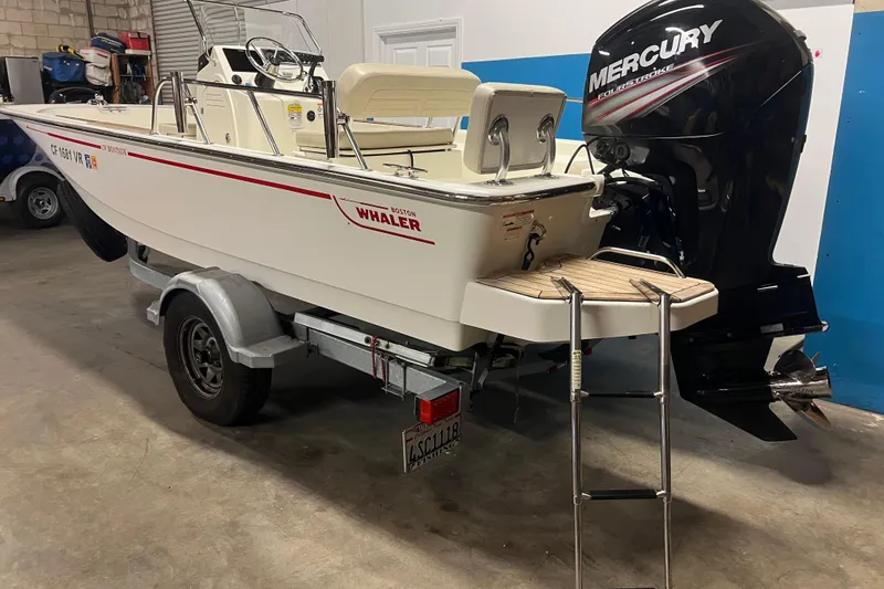 Slide: The Image of 2019 Boston Whaler 170 Montauk boat with Mercury engine on trailer in garage. - 2