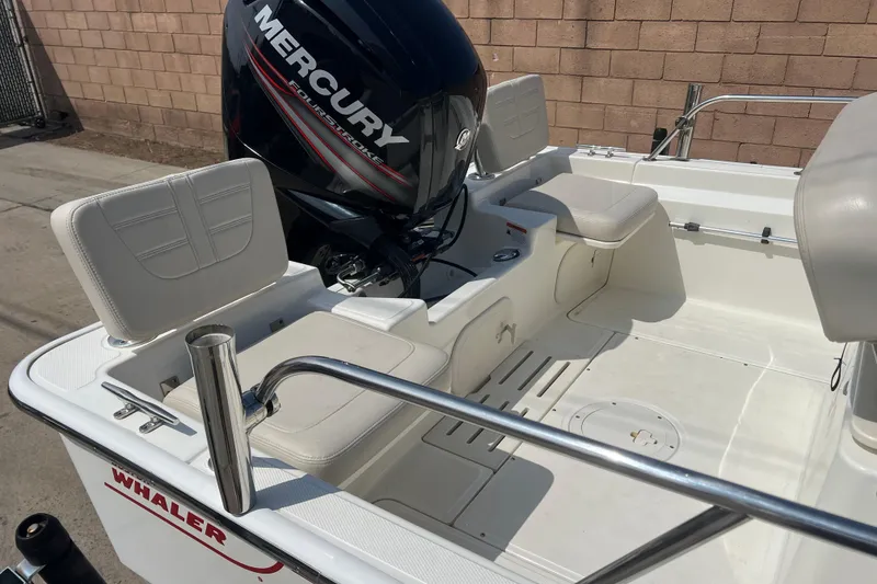 Slide: The Image of 2019 Boston Whaler 170 Montauk boat interior with Mercury engine, white seating, and railing. - 20