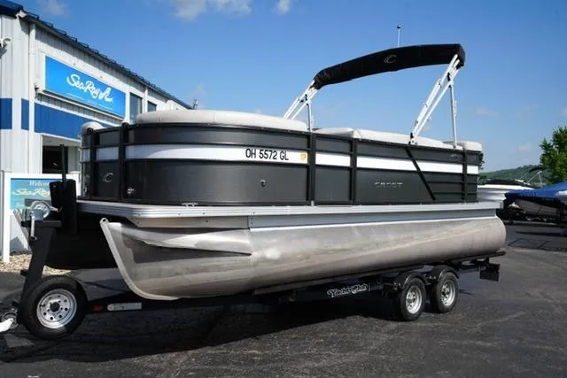 Slide: The Image of 2021 Crest Classic DLX 200 L pontoon boat on trailer, parked outside a building. - 2