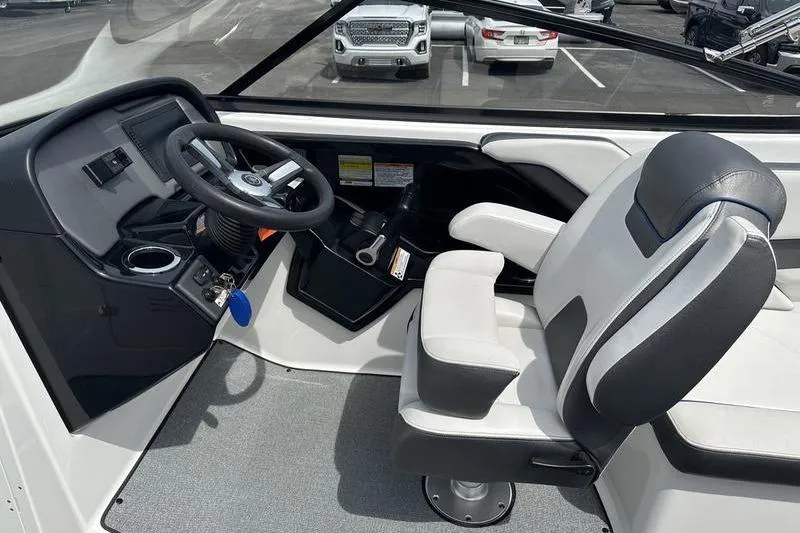 Slide: The Image of 2020 Yamaha Boats SX240 cockpit with steering wheel and captain's chair in a parking lot. - 16