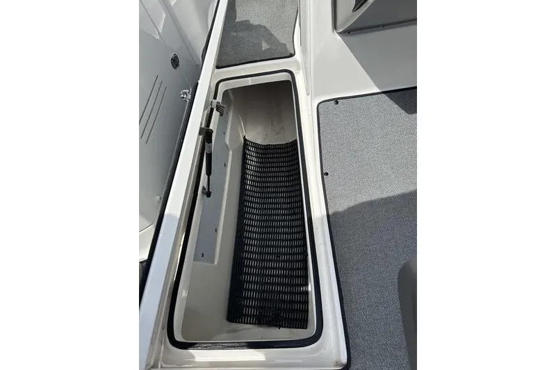 Slide: The Image of 2020 Yamaha Boats SX240 storage compartment with non-slip mat and gray flooring. - 36