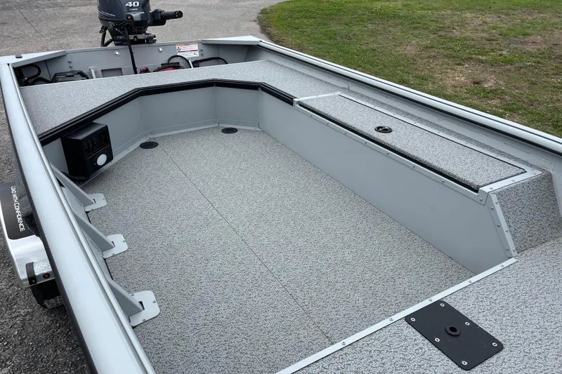 Slide: The Image of 2026 SeaArk DXS 1652 DKLD boat interior with gray flooring and storage compartments. - 12