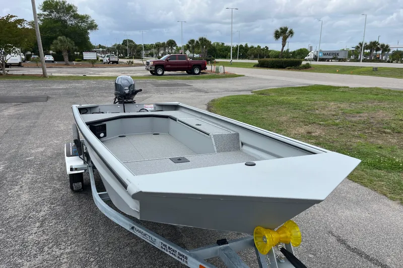 Slide: The Image of 2026 SeaArk DXS 1652 DKLD boat on trailer, parked outdoors under cloudy sky. - 6
