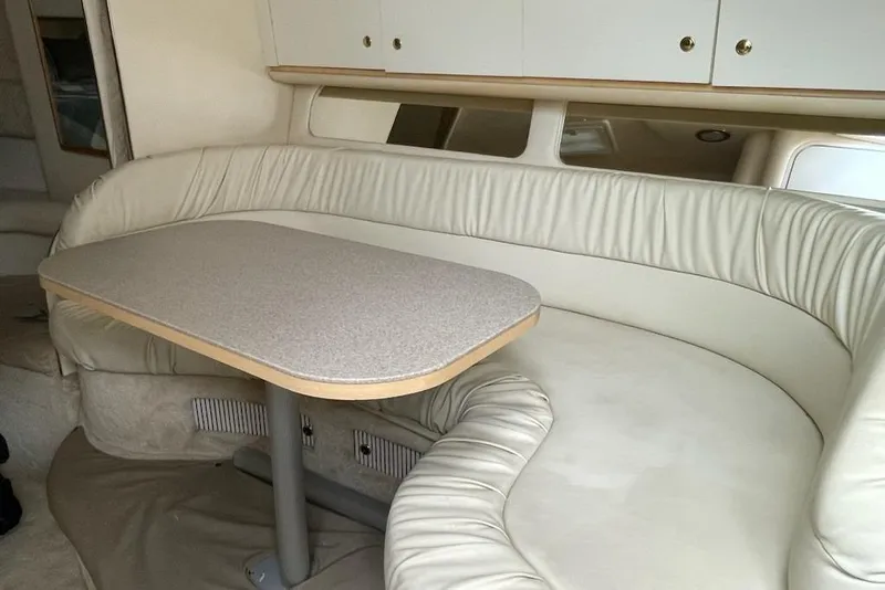 Slide: The Image of Interior of 2000 Sea Ray 290 Sundancer with beige leather seating and table. - 11