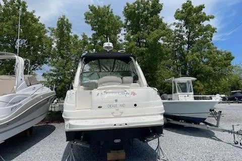 Slide: The Image of 2000 Sea Ray 290 Sundancer boat on dry dock, surrounded by trees and other boats. - 3