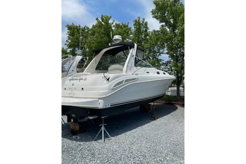 Slide: The Image of 2000 Sea Ray 290 Sundancer boat on stands, surrounded by trees and gravel. - 4