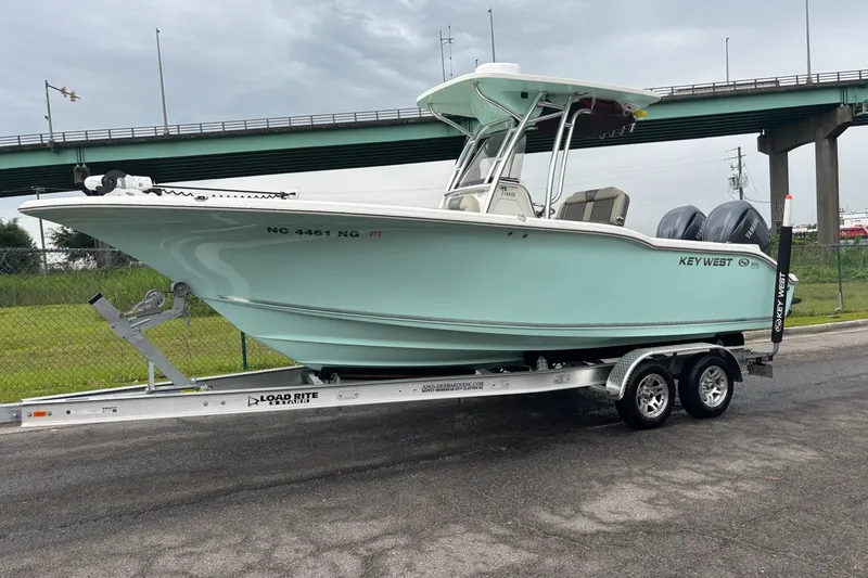 The Image of 2025 Key West 244 Center Console boat on trailer, parked near a bridge. - 1
