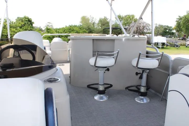 Slide: The Image of 2015 South Bay 524E pontoon boat interior with bar stools and helm. - 12