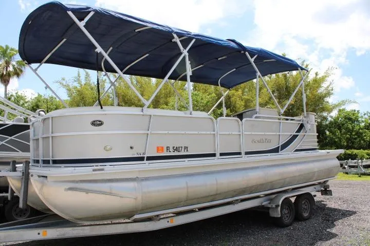 Slide: The Image of 2015 South Bay 524E pontoon boat with blue canopy on a trailer. - 2