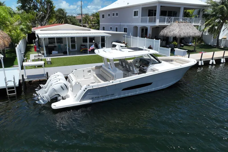 The Image of 2022 Regal 38 SAV boat docked by waterfront home with lush greenery. - 0