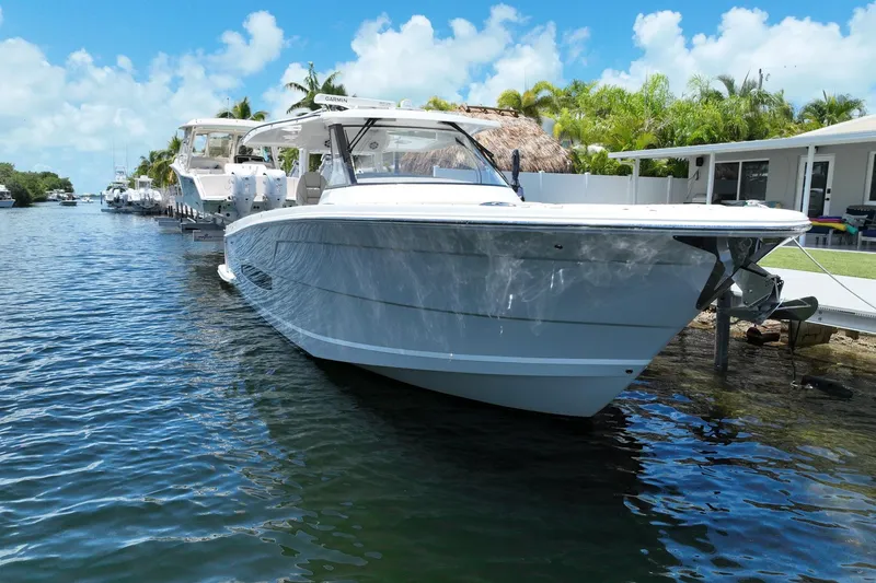 Slide: The Image of 2022 Regal 38 SAV boat docked on a sunny day, surrounded by palm trees. - 1