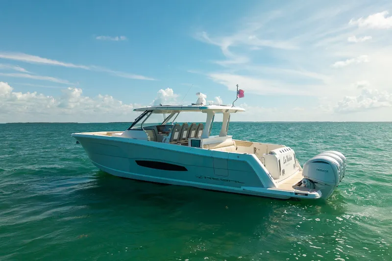 Slide: The Image of 2022 Regal 38 SAV boat cruising on clear blue ocean under sunny skies. - 2