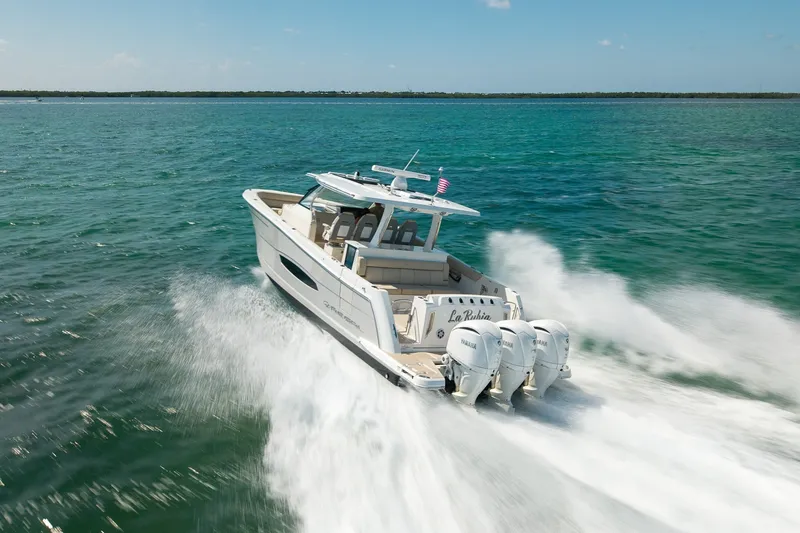 Slide: The Image of 2022 Regal 38 SAV boat cruising on open water with triple outboard engines. - 16