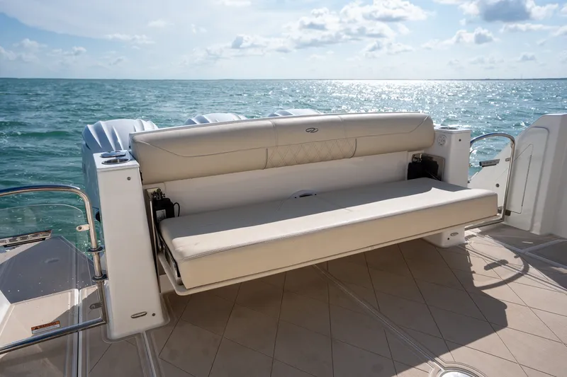 Slide: The Image of 2022 Regal 38 SAV boat with beige seating, overlooking the ocean under a sunny sky. - 22