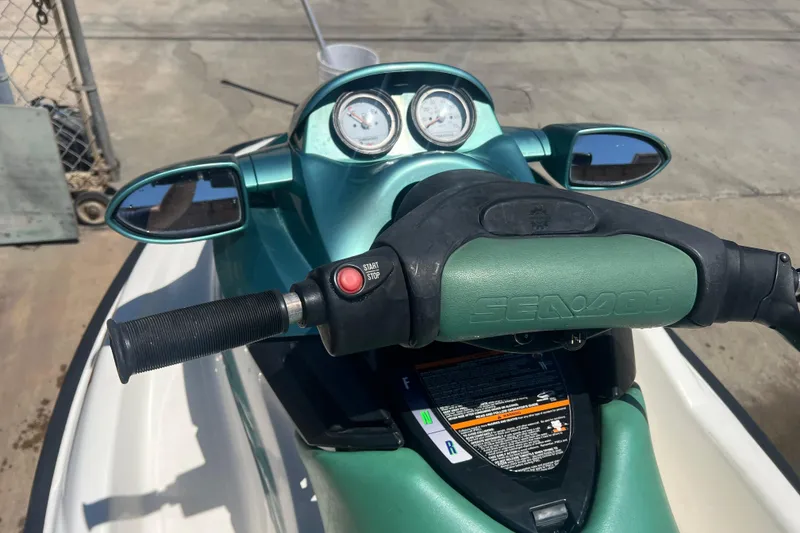 Slide: The Image of 2001 Sea-Doo GTI jet ski handlebars with mirrors and gauges, parked on concrete. - 3
