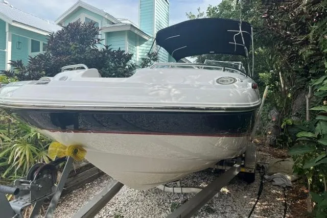 Slide: The Image of 2015 Hurricane SunDeck 2400 OB boat on trailer, parked near tropical foliage. - 1