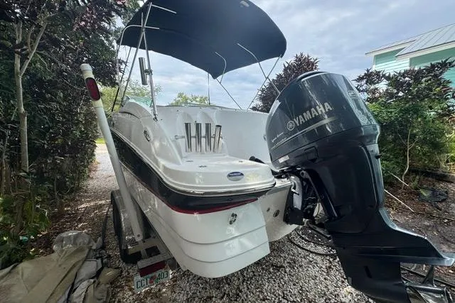 Slide: The Image of 2015 Hurricane SunDeck 2400 OB boat with Yamaha outboard motor, parked on gravel driveway. - 2