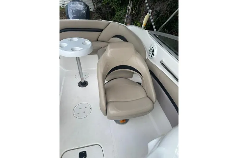 Slide: The Image of 2015 Hurricane SunDeck 2400 OB boat interior with beige seating and cup holder table. - 22