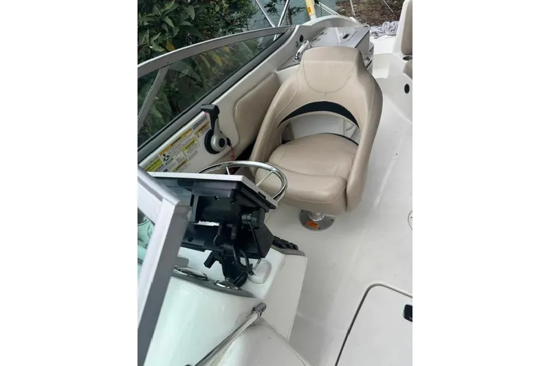 Slide: The Image of 2015 Hurricane SunDeck 2400 OB boat interior with beige seating and steering wheel. - 23