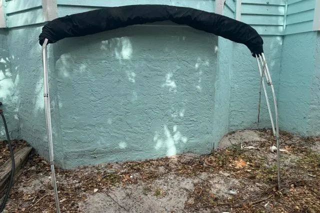Slide: The Image of Bimini top for 2015 Hurricane SunDeck 2400 OB, set against a light blue wall. - 27