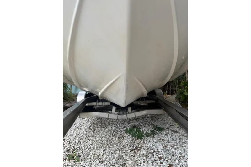Slide: The Image of 2015 Hurricane SunDeck 2400 OB boat hull on trailer, resting on gravel. - 5