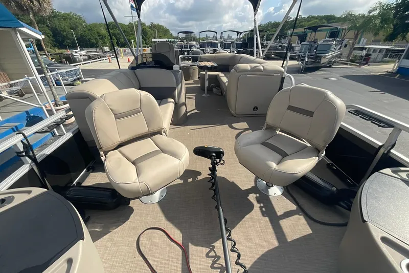 Slide: The Image of 2021 Sun Tracker Fishin' Barge 20 DLX interior with beige seating and fishing equipment. - 10