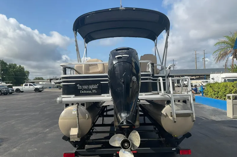 Slide: The Image of 2021 Sun Tracker Fishin' Barge 20 DLX pontoon boat with outboard motor, parked outdoors. - 4