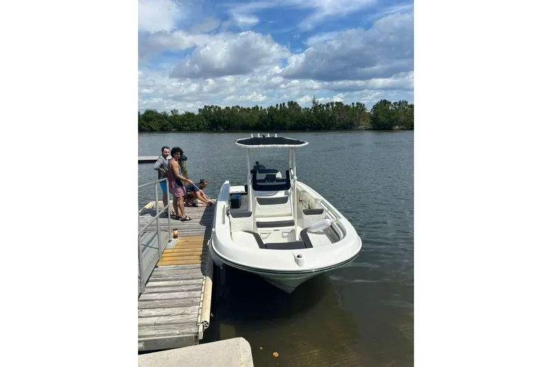 Slide: The Image of 2023 Bayliner Trophy T22CC docked by a lake with people nearby. - 2