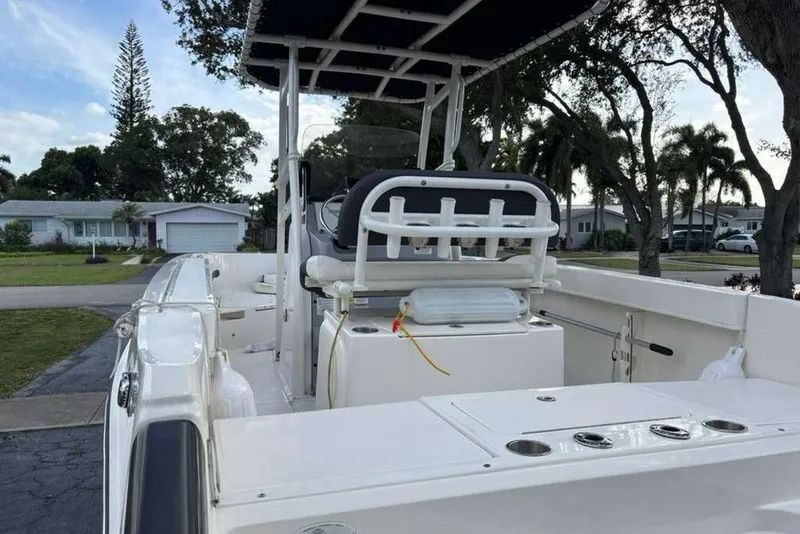 Slide: The Image of 2023 Bayliner Trophy T22CC boat with seating and rod holders, parked in a residential area. - 6